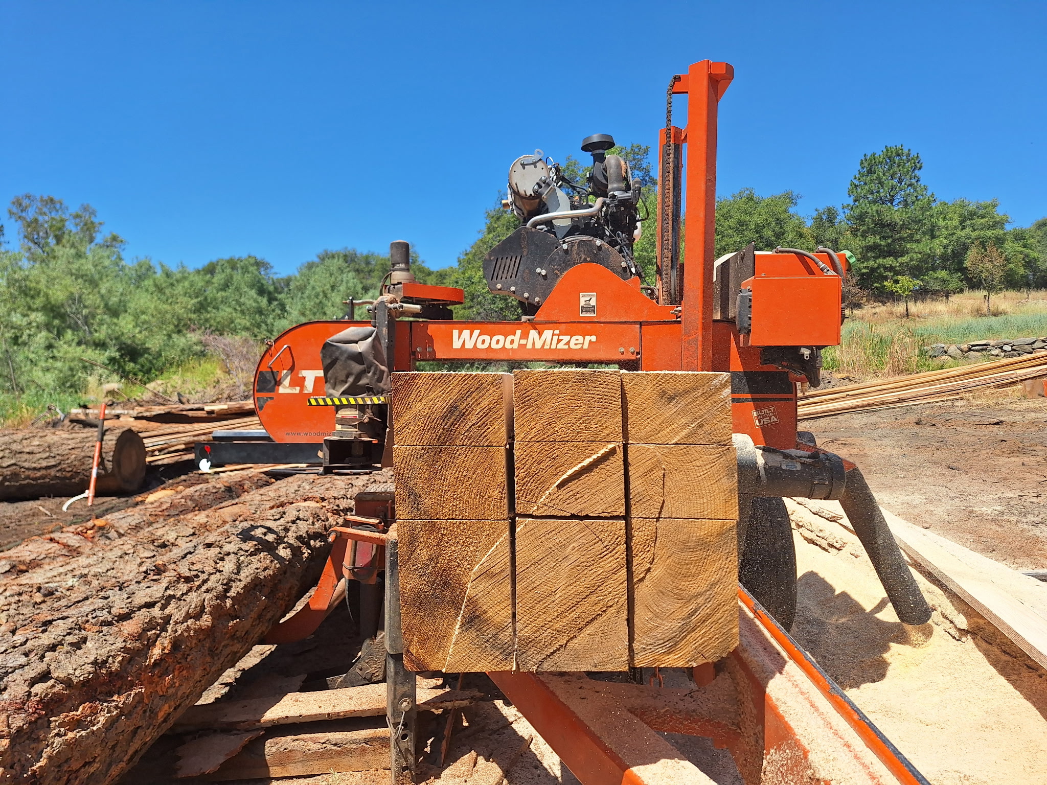 Sawmill cutting a large timber outdoors.